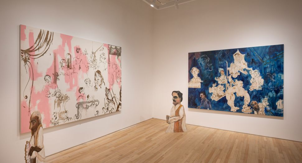 Two large paintings—one in pink and white, one in deep blue—hang in a gallery space with a small painted cut-out figure placed on the floor between them.