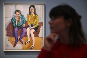 A gallery assistant poses for a photograph with an artwork entitled 'Wellesley Girls, 1967' by US artist Alice Neel during a press preview of 'Alice Neel: Hot Off The Griddle' at the Barbican Art Gallery in London on February 15, 2023.