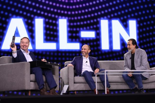 Three men sit onstage for a talk.