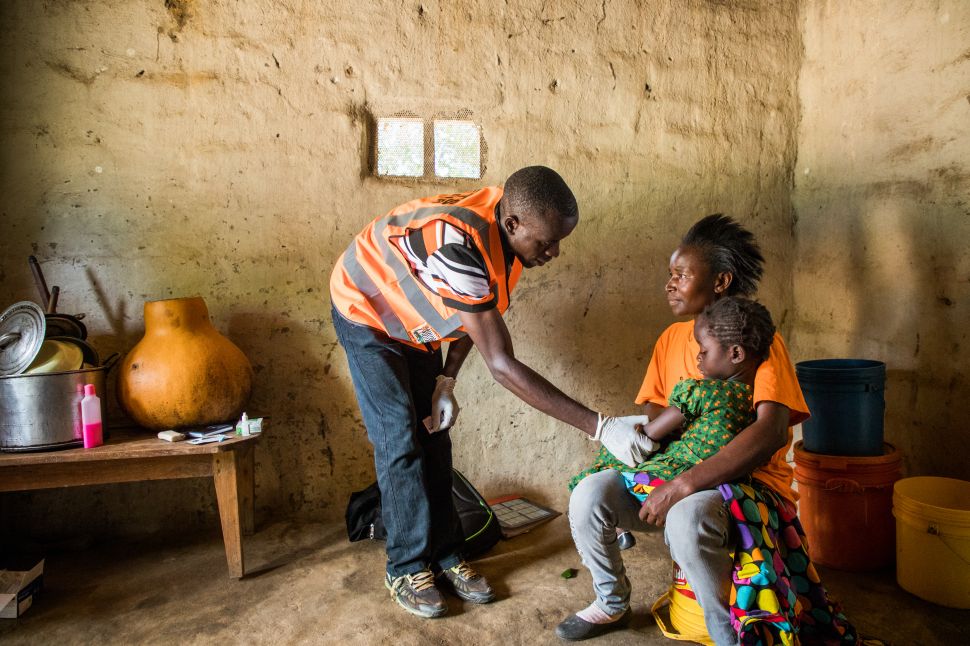 Man leans down to speak to child sitting on a woman's lap 