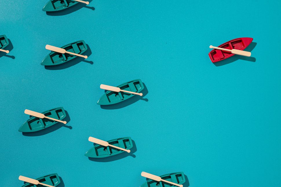 Blue boats moving in one direction while a red boat is separated from the group, moving in the opposite direction