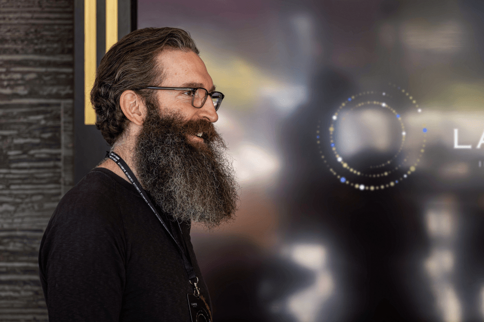 Bearded man in black T-shirt pictured outside window